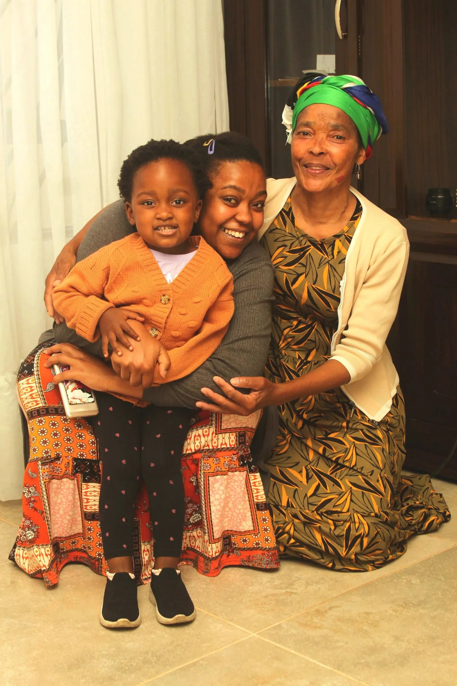 Grandmother, mother and young child smiling together at home